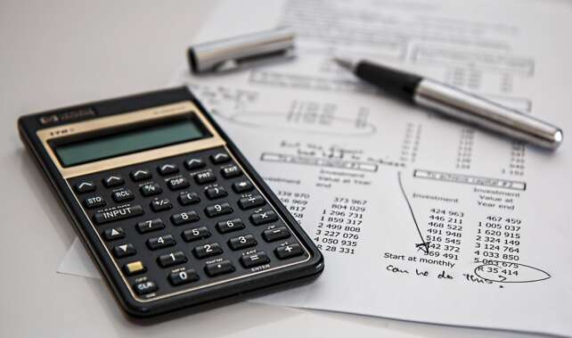 calculator and pen on investment return calculation sheet