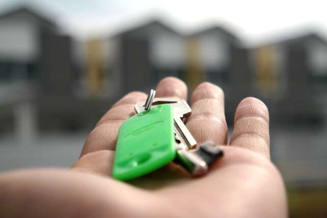 a hand holding keys in front of a house