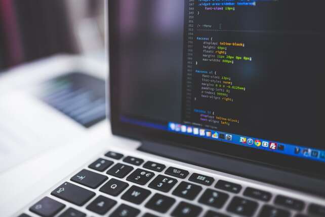 programmer laptop with lines of code. Constellation Software buys WideOrbit and spins out Lumine Group