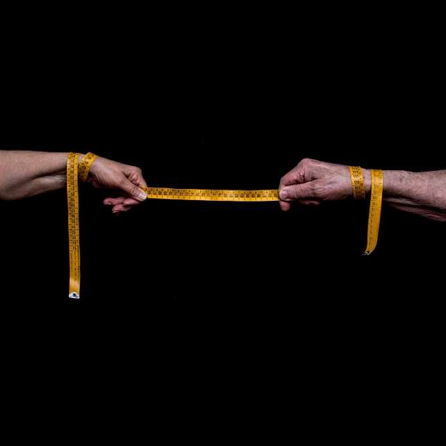 2 hands holding a tape measurer on a black background