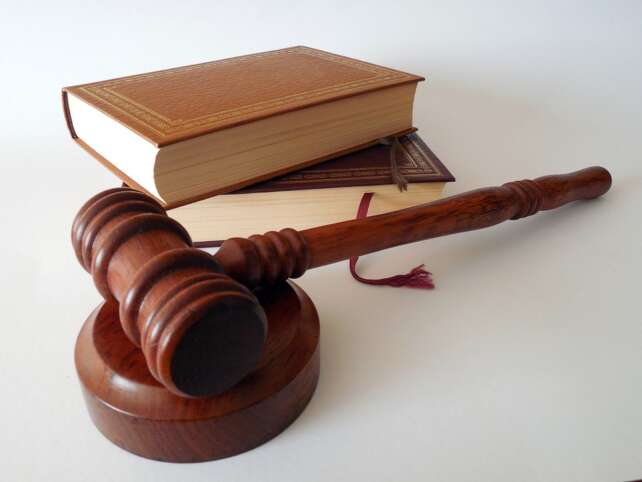 a mallet hammer representing the law and a book of rules and regulations on a desk