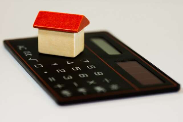 toy house on a calculator on a table, representing the important of budgeting